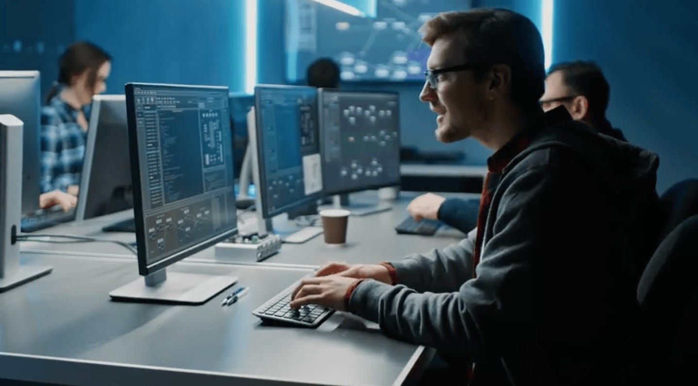 Advanced IT support team working on multiple computer screens in a modern tech office.